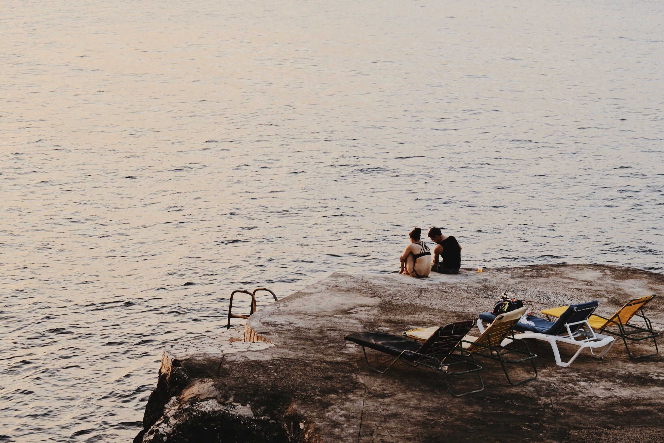 a couple sitting on the cliff located in Negril, Jamaica